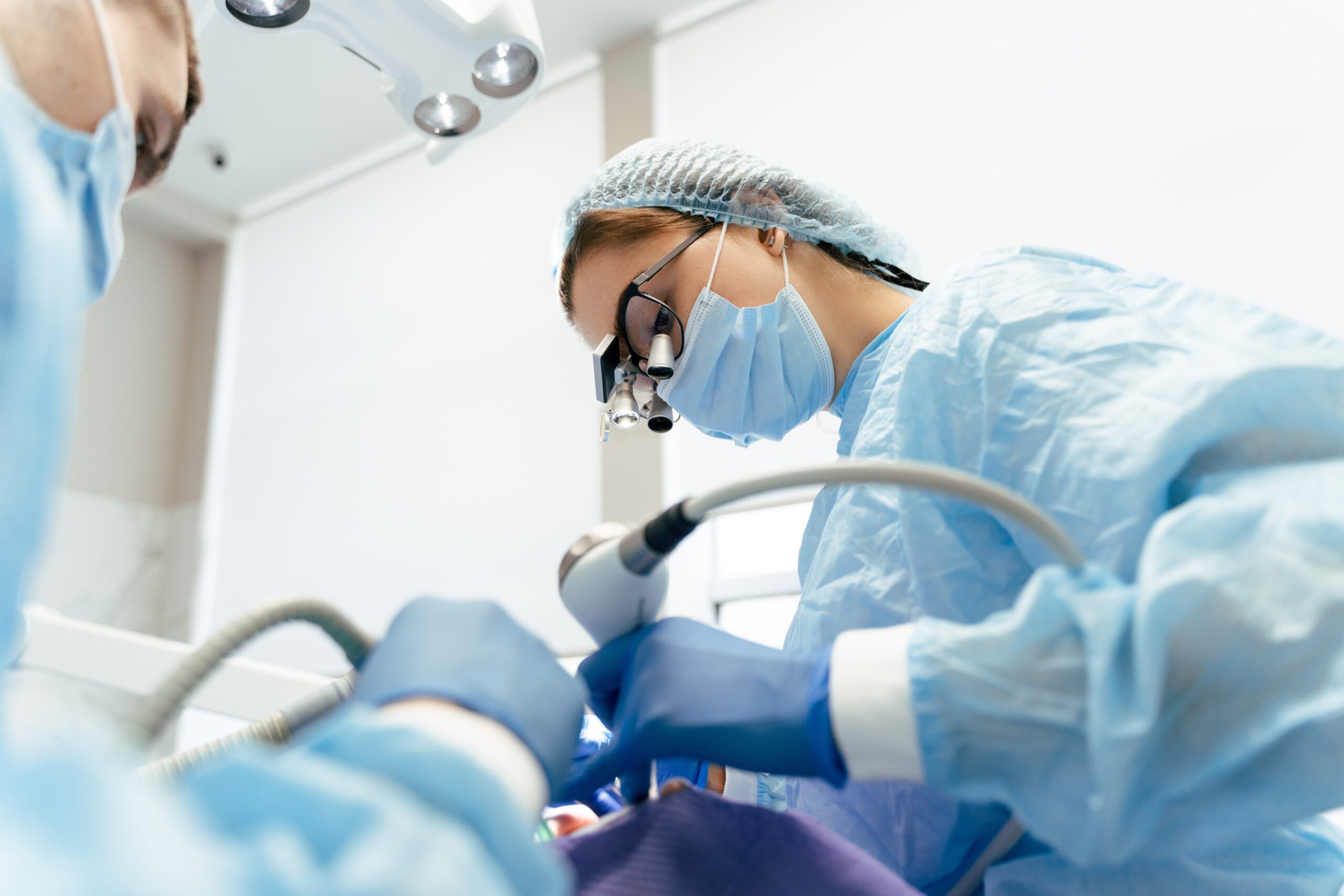 Portrait,Of,Female,Dentist,In,Binoculars,And,Surgical,Suit,,Using